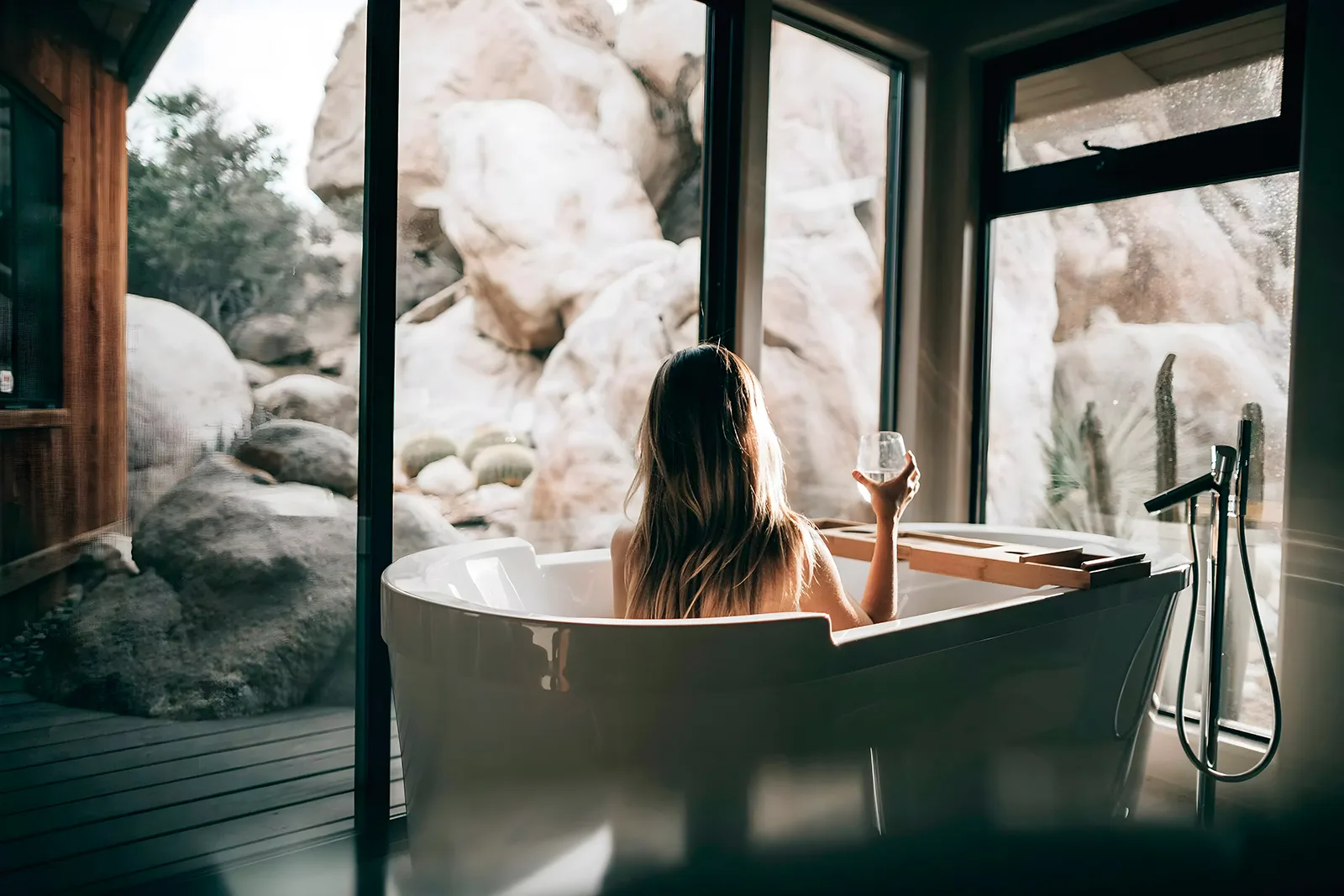 Freestanding bathtub with water glass and natural rock view